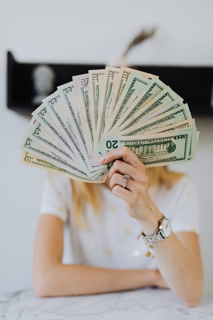 services-02 A person holding a fan of US dollar bills, symbolizing wealth and financial success.